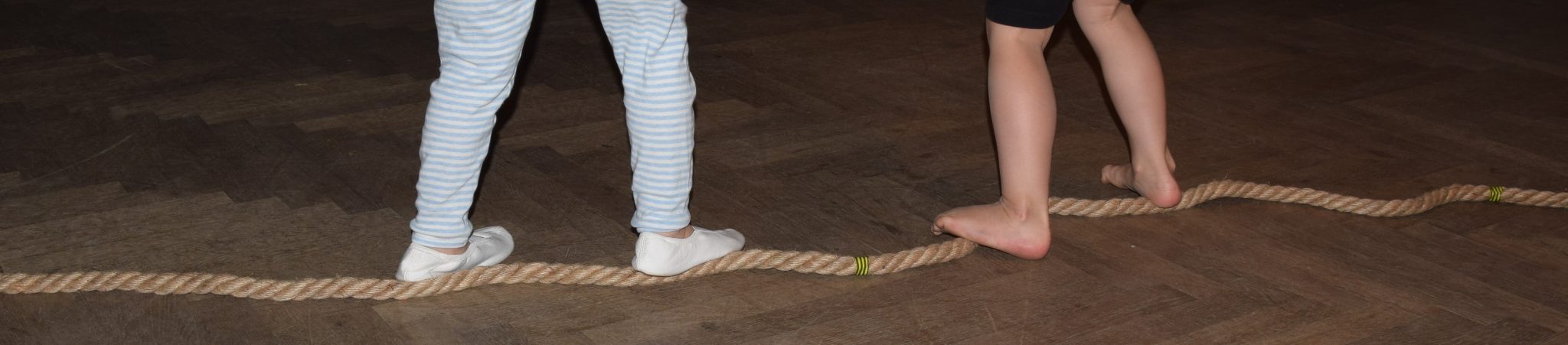 Kleinkinder balancieren auf einem Seil beim Eltern-Kind-Tanzen